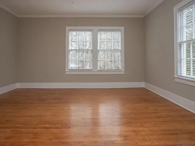 a view of an empty room with wooden floor and a window