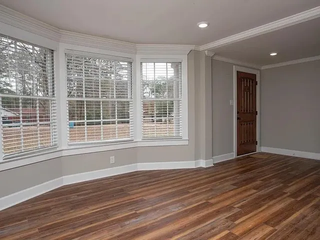 a view of an empty room with wooden floor and a window
