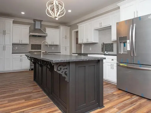 a kitchen with stainless steel appliances granite countertop a sink a stove a refrigerator and island with wooden floor