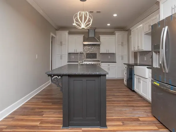 a kitchen with kitchen island granite countertop a sink a counter space stainless steel appliances and cabinets