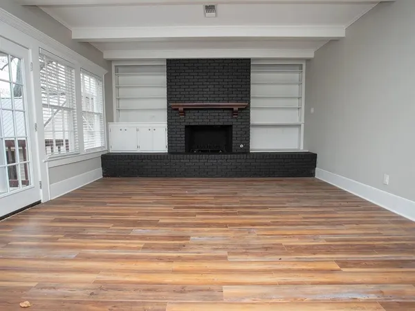 a view of empty room with wooden floor and fireplace