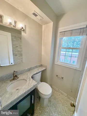 a bathroom with a granite countertop sink a toilet and a mirror