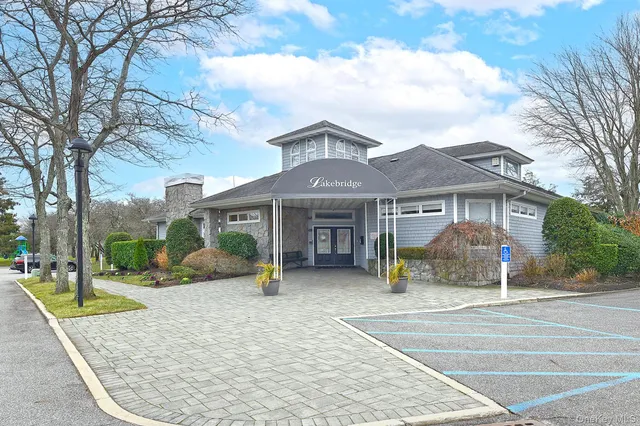 a view of a white house with many windows plants and large tree