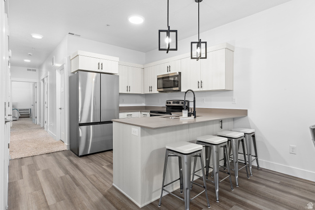 4735 Alder Drive, Unit F101 Mapleton, UT 84664 - Photo 9 of 30 Kitchen with stainless steel appliances, a kitchen breakfast bar, light wood finished floors, and a peninsula
