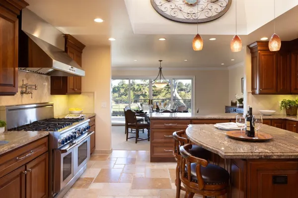 a kitchen with kitchen island granite countertop a stove a sink a dining table and chairs