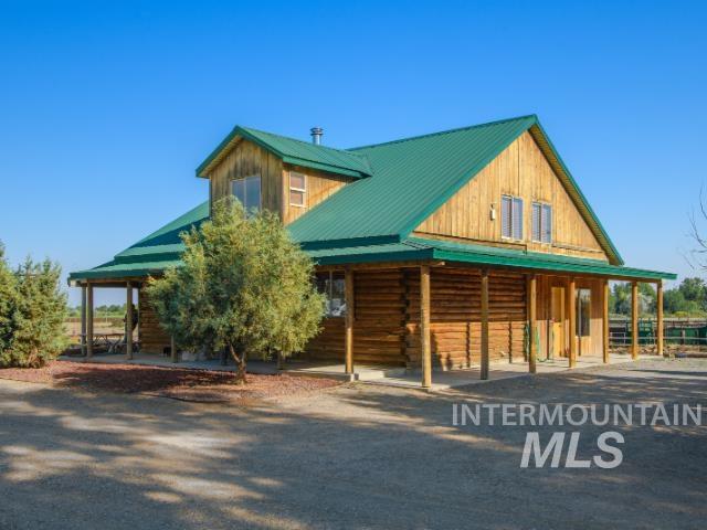 6891 West 2000 South Rexburg, ID 83440 - Photo 35 of 50 View of front facade with a metal roof, an exterior structure, covered porch, an outbuilding, and log siding