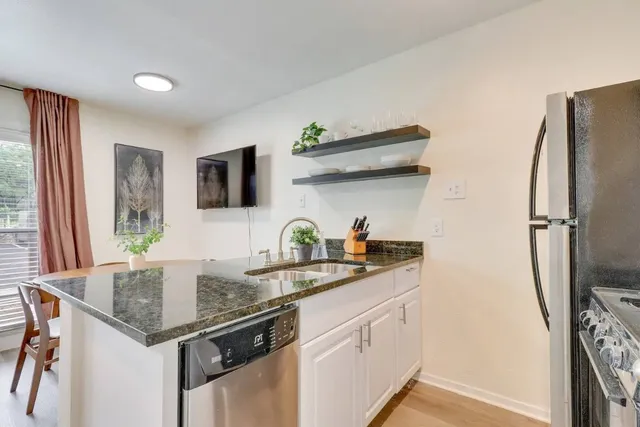 a kitchen with stainless steel appliances granite countertop a sink a refrigerator and a granite counter tops