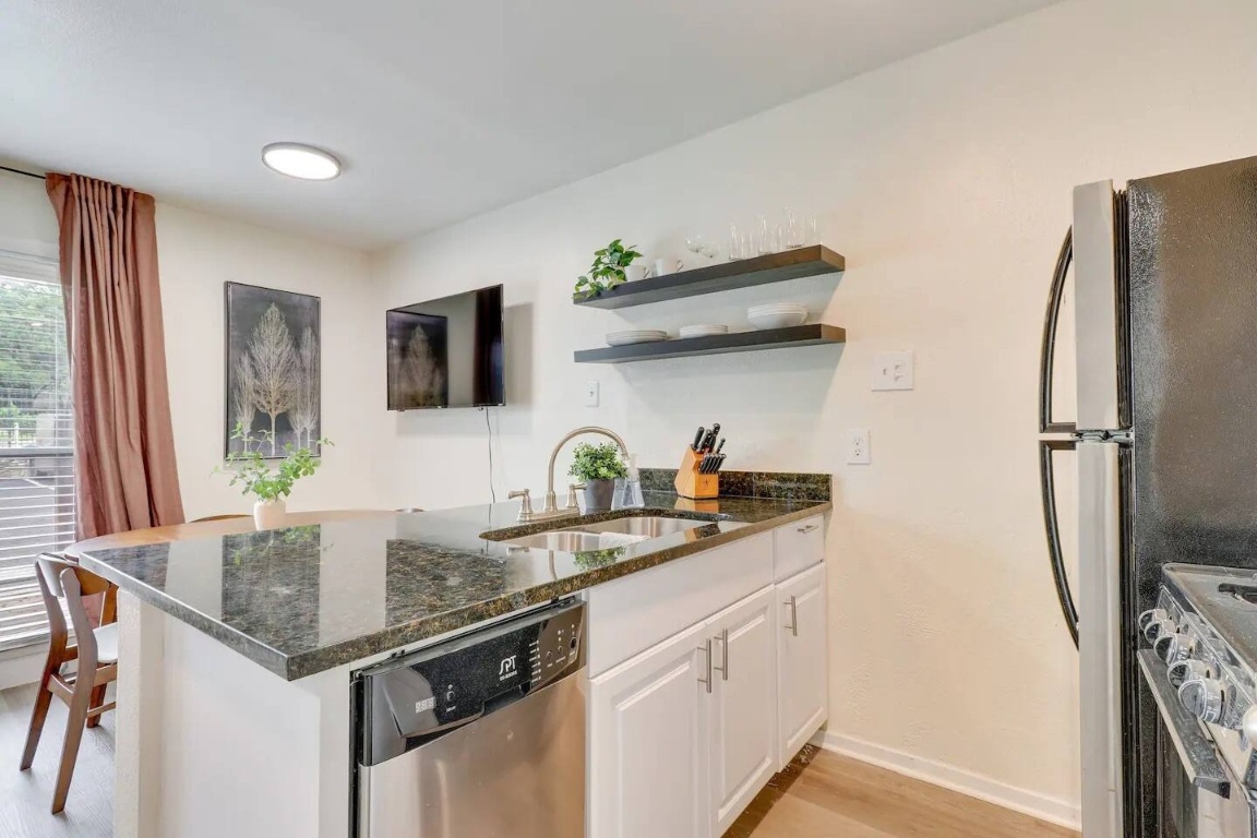 2401 Manor Road, Unit 129 Austin, TX 78722 - Photo 15 of 21 a kitchen with stainless steel appliances granite countertop a sink a refrigerator and a granite counter tops