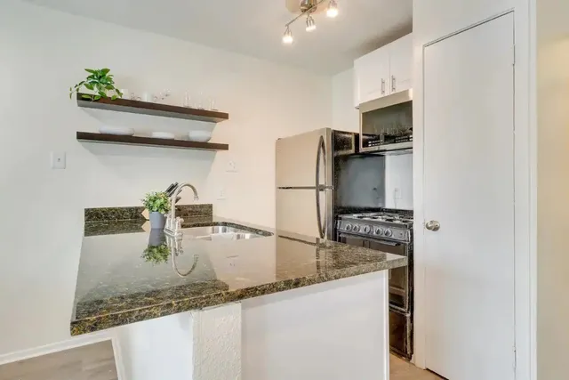 a kitchen with stainless steel appliances granite countertop a sink and a refrigerator