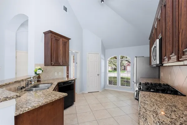 a kitchen with stainless steel appliances granite countertop a stove a sink and a microwave