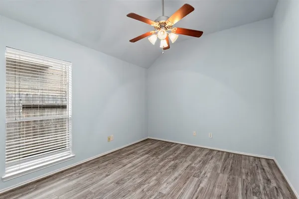 a view of an empty room with wooden floor and windows