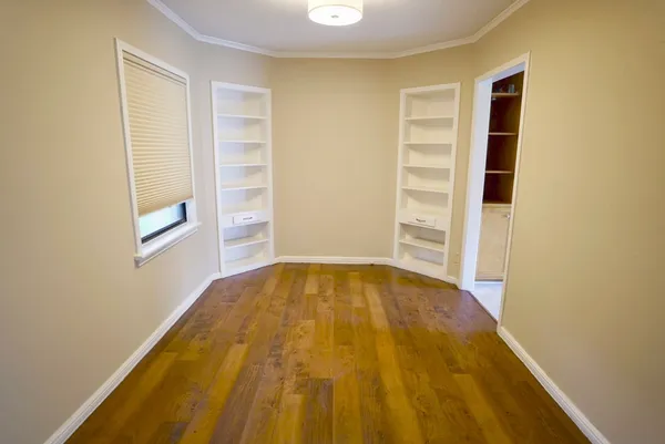 a view of an empty room with wooden floor and closet
