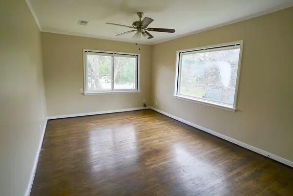 a view of an empty room with wooden floor and a window