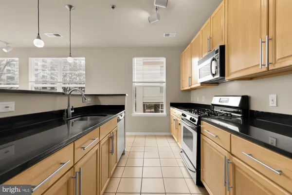a kitchen with stainless steel appliances granite countertop a sink a stove and a wooden floors