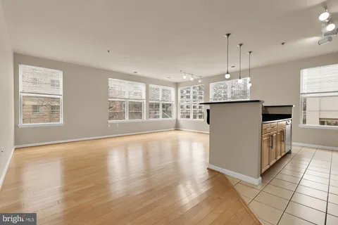 a kitchen with stainless steel appliances granite countertop a refrigerator a sink dishwasher a oven and a dining table with wooden floor