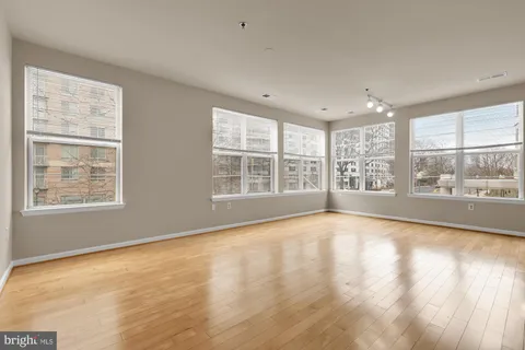 a view of an empty room with a window and wooden floor