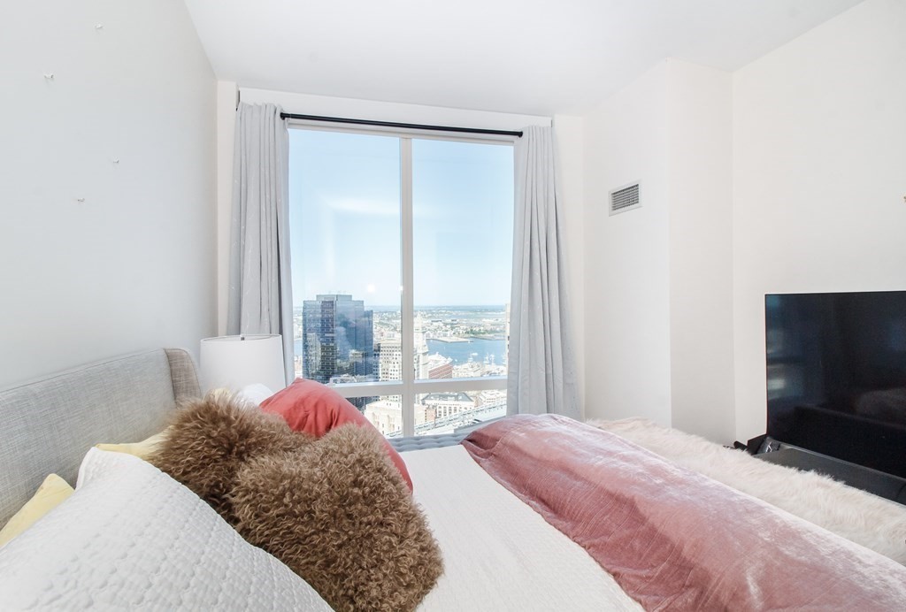 1 Franklin Street, Unit 5205 Boston, MA 02110 - Photo 17 of 40 a bedroom with a bed and a flat tv screen next to a window