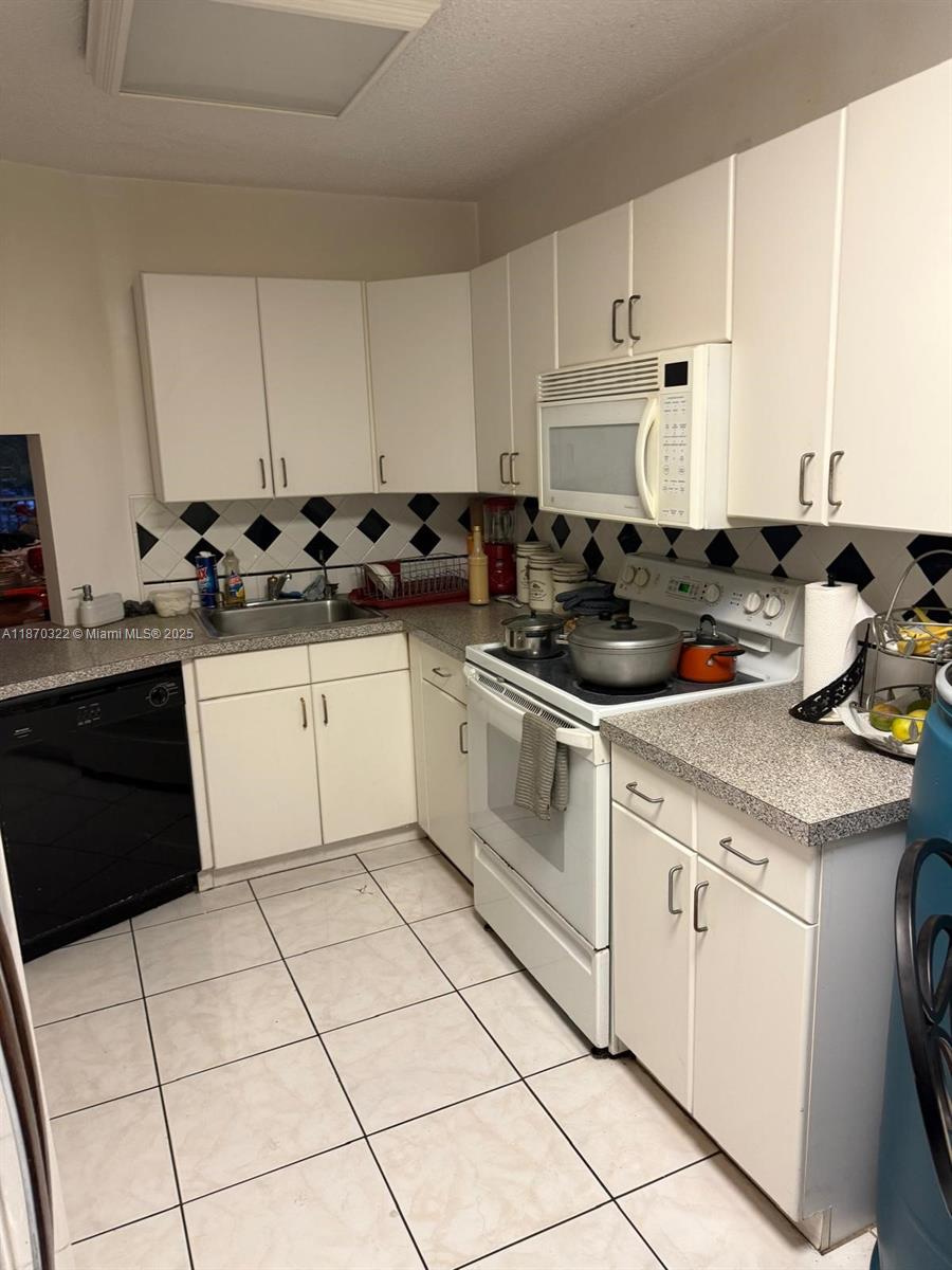 1710 Northeast 191st Street, Unit 3173 Miami, FL 33179 - Photo 18 of 18 a kitchen with a sink a stove and white cabinets
