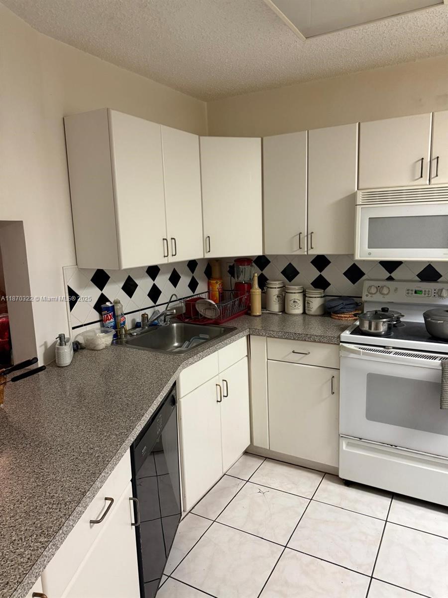 1710 Northeast 191st Street, Unit 3173 Miami, FL 33179 - Photo 10 of 18 a kitchen with granite countertop a sink a stove and cabinets
