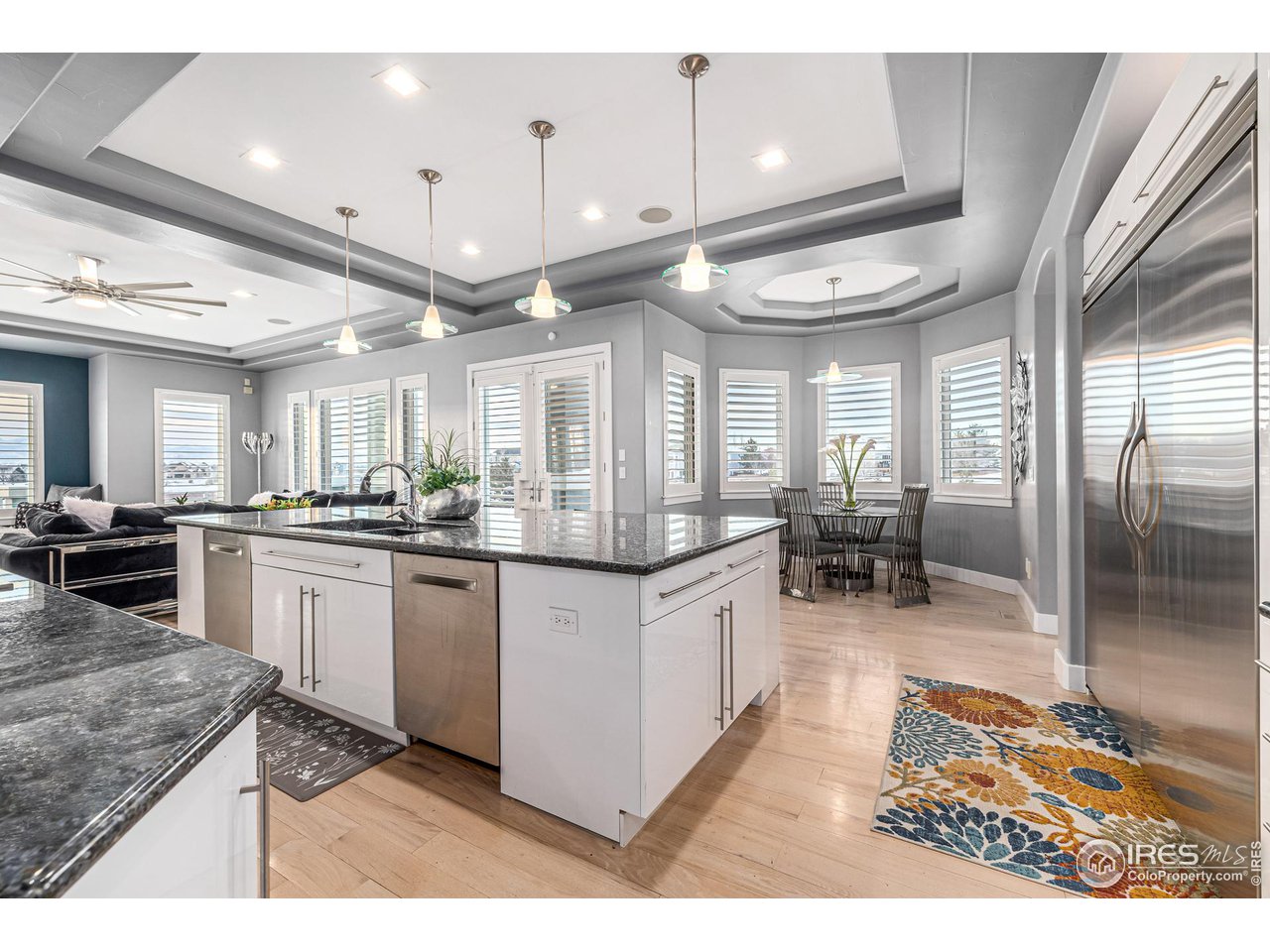285 Commander Drive Erie, CO 80516 - Photo 14 of 40 a kitchen with stainless steel appliances kitchen island granite countertop a table chairs and a refrigerator