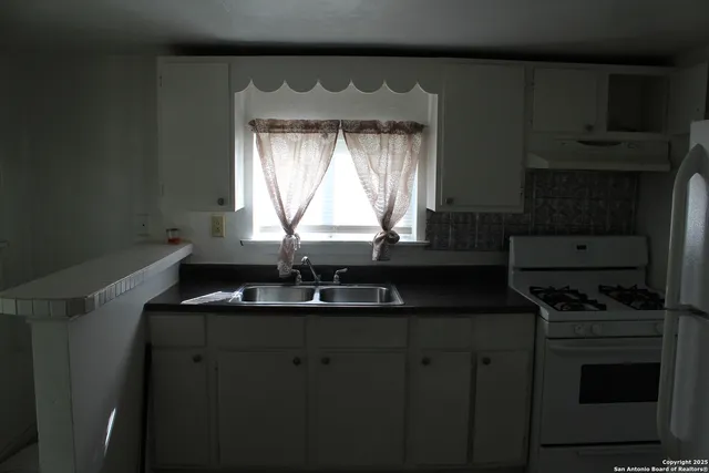 a kitchen with granite countertop a sink a stove and cabinets