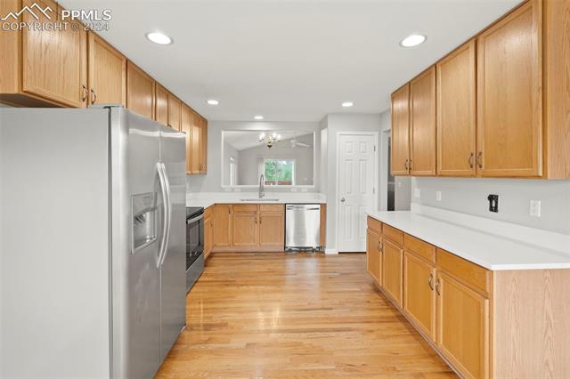 6725 Akron Road Colorado Springs, CO 80923 - Photo 7 of 50 Kitchen with light brown cabinetry, a chandelier, sink, appliances with stainless steel finishes, and light hardwood / wood-style flooring