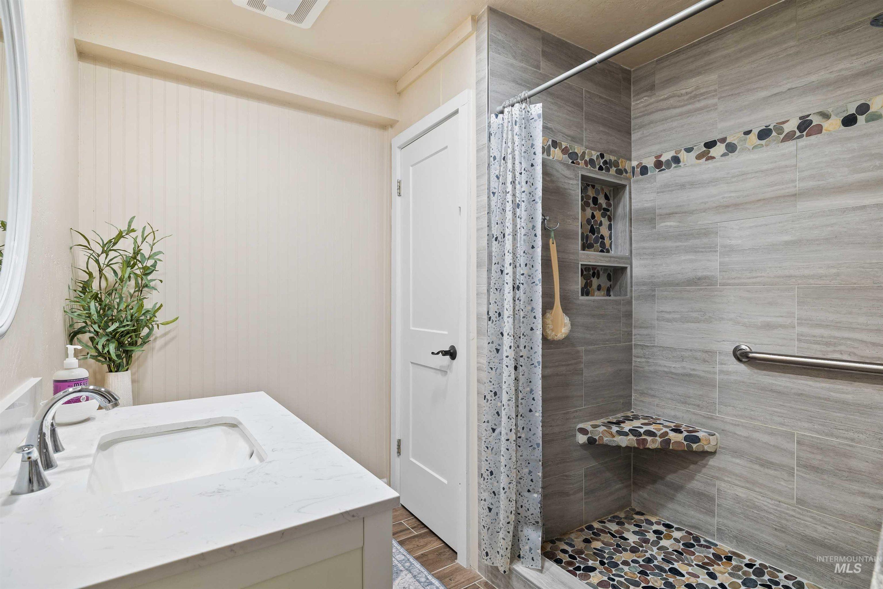 11 Bell Rapids Road Hagerman, ID 83332 - Photo 34 of 40 Bathroom featuring a walk-in shower with stone tile walls, pebble floor, built-in bench, and dual recessed niches