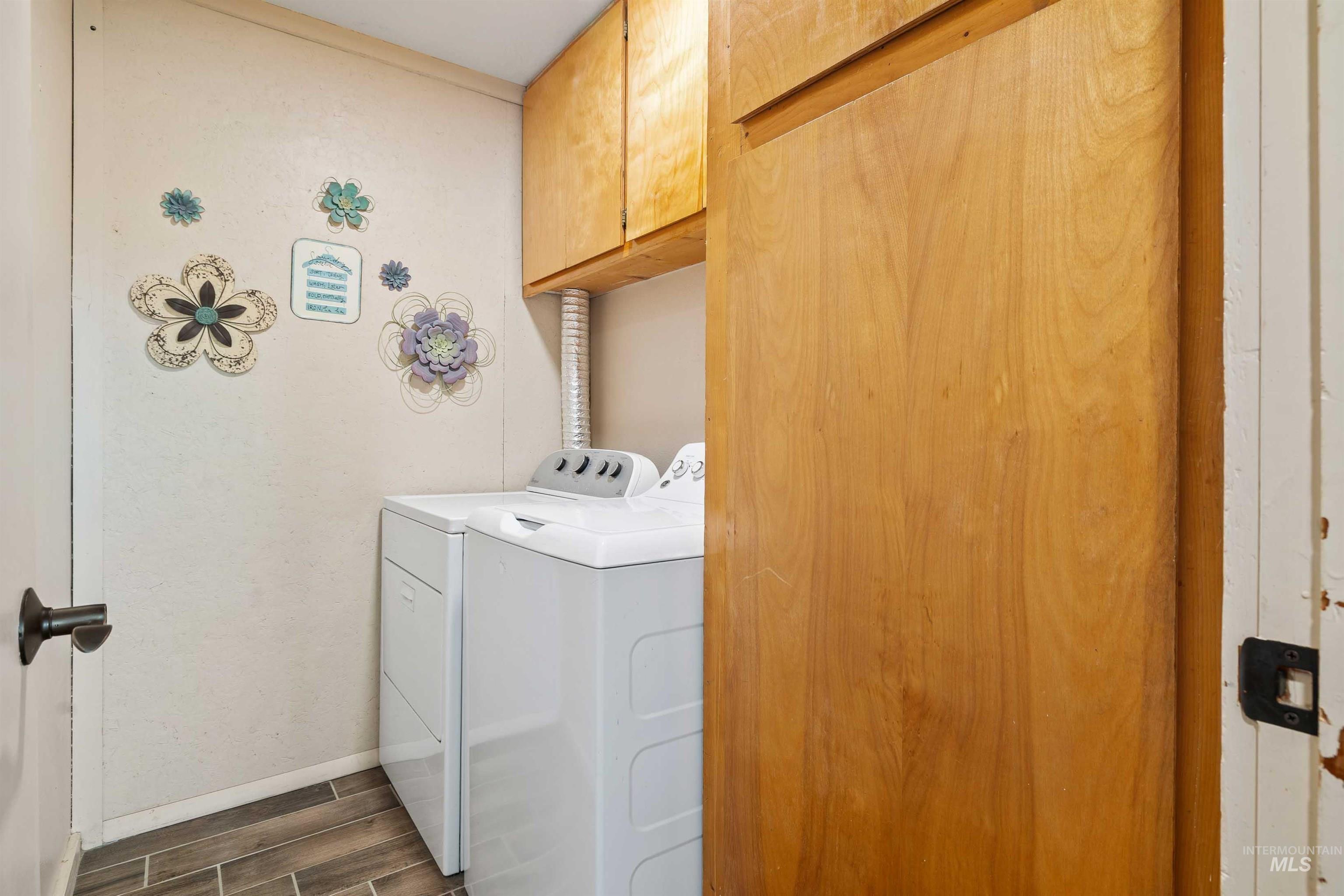 11 Bell Rapids Road Hagerman, ID 83332 - Photo 36 of 40 Compact laundry space featuring wood-finish cabinetry, tile flooring, and a sliding wood-finish door