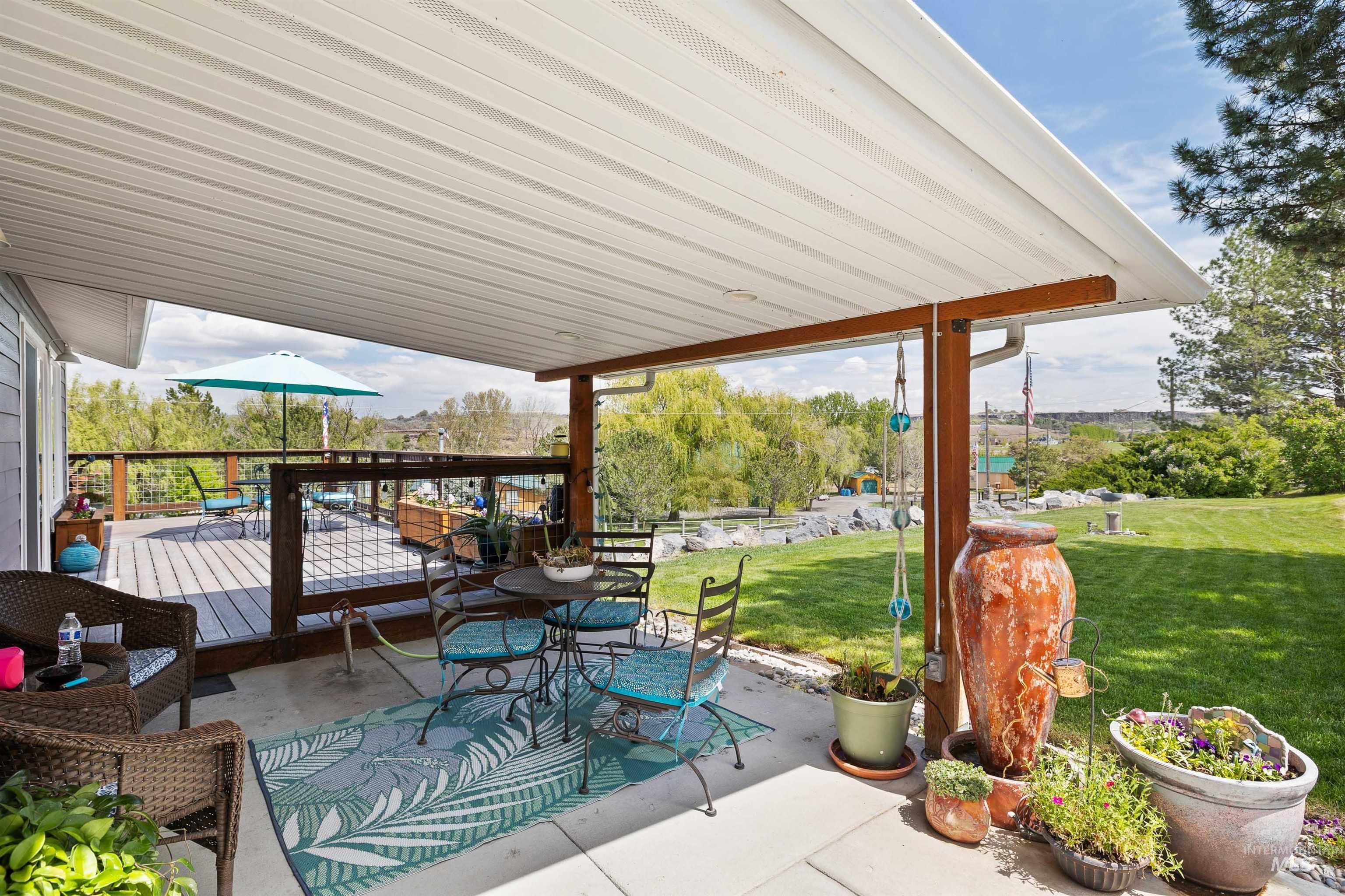 11 Bell Rapids Road Hagerman, ID 83332 - Photo 6 of 40 Covered concrete patio with a wood-framed deck, metal railing, and expansive lawn