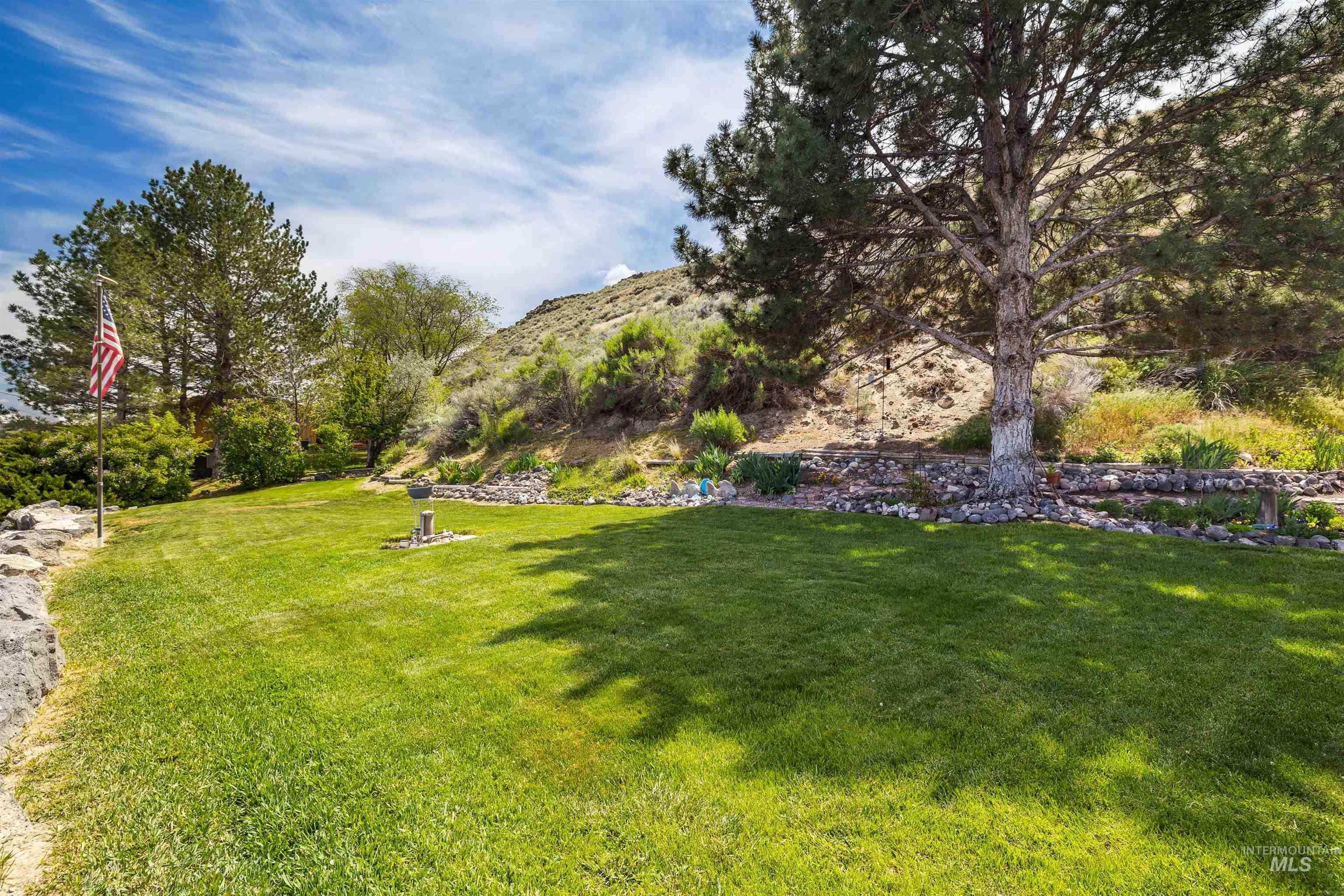 11 Bell Rapids Road Hagerman, ID 83332 - Photo 7 of 40 Expansive green lawn with mature trees and a natural rock retaining wall