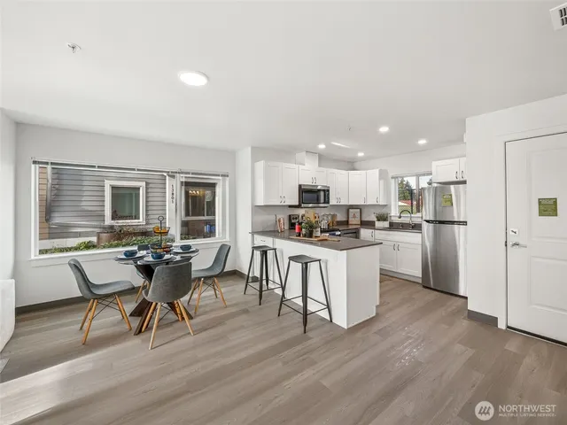 a kitchen with a dining table chairs wooden floor appliances and cabinets