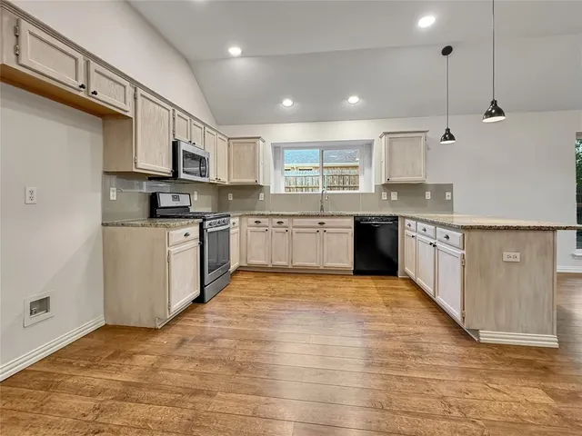 a large kitchen with stainless steel appliances granite countertop a stove top oven a sink dishwasher and a refrigerator