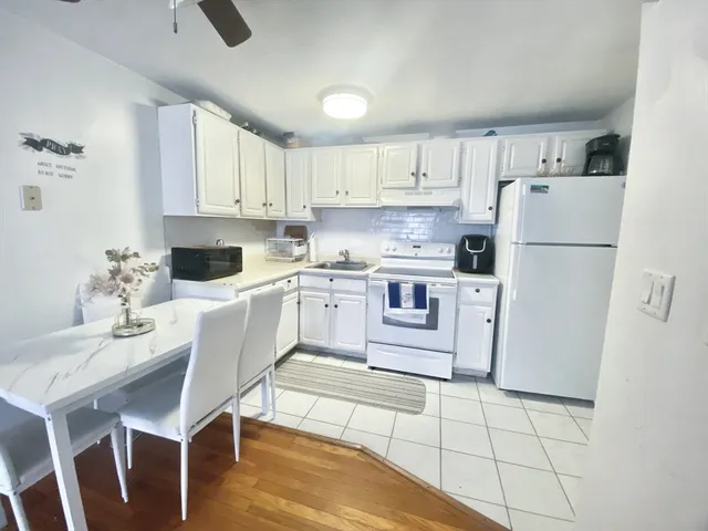 a kitchen with a sink a stove a refrigerator and white cabinets