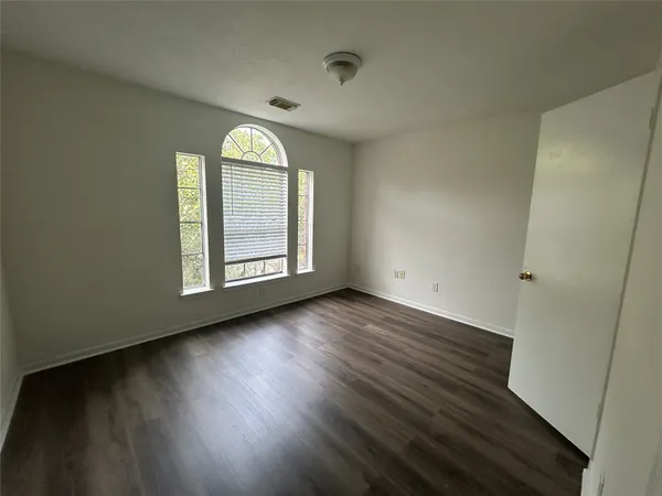 an empty room with wooden floor windows and entrance