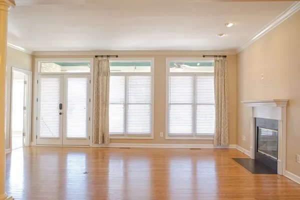 a view of an empty room with wooden floor and a fireplace