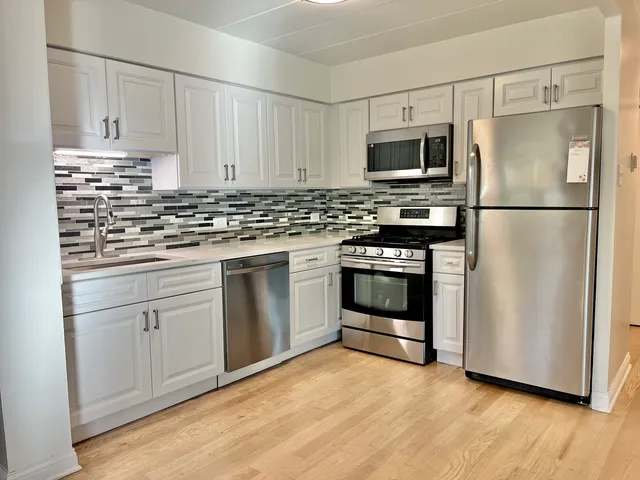 a kitchen with white cabinets and stainless steel appliances