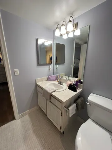 a bathroom with a sink a large mirror and a toilet