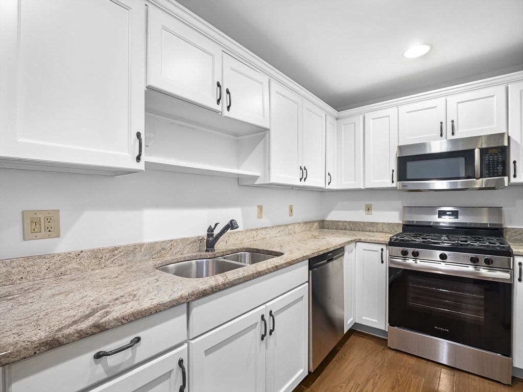 600 County Street, Unit 404 Taunton, MA 02780 - Photo 2 of 26 a kitchen with granite countertop a sink dishwasher stove and microwave with wooden cabinets