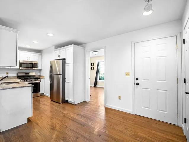 a view of a kitchen with refrigerator and wooden floor