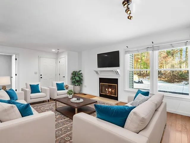 a living room with furniture fireplace and a large window