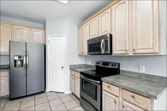 a kitchen with stainless steel appliances granite countertop white cabinets a refrigerator and a stove top oven