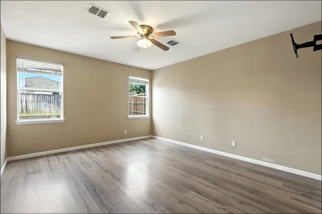 a view of an empty room with wooden floor and a window