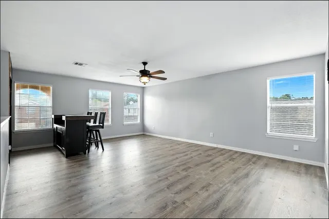 a view of a livingroom with furniture hardwood floor ceiling fan and windows