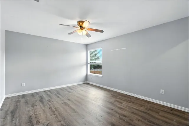a view of an empty room with a window and wooden floor