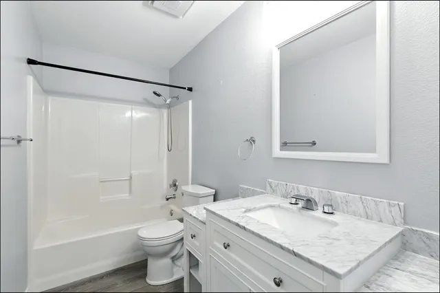 a bathroom with a granite countertop sink toilet and shower