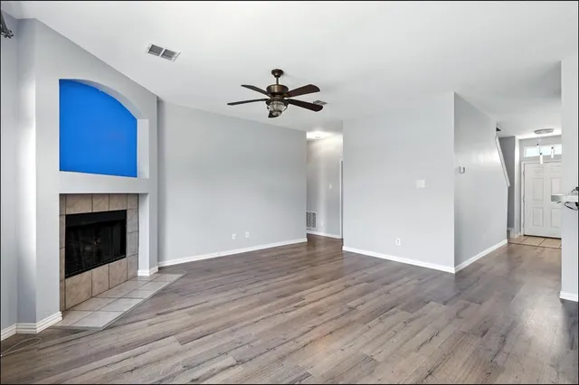 a view of an empty room with wooden floor and a fireplace