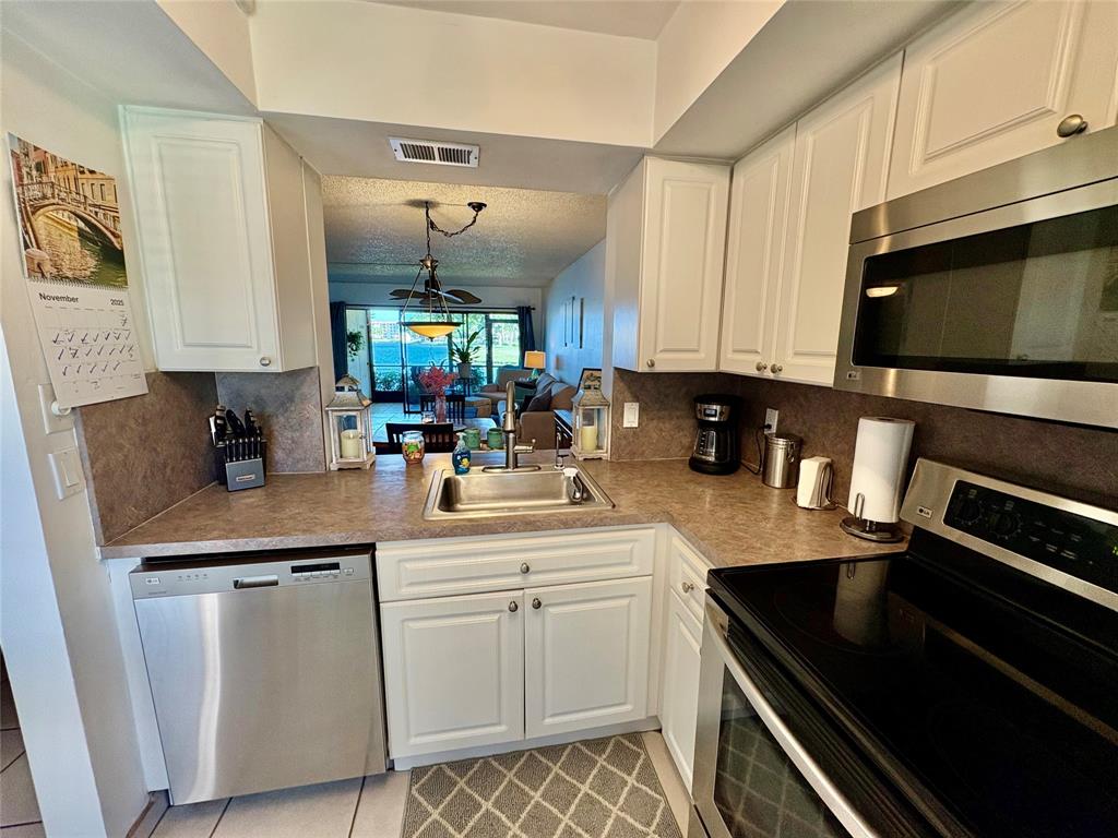 2249 Southwest 15th Street, Unit 185 Deerfield Beach, FL 33442 - Photo 13 of 31 a kitchen with stainless steel appliances white cabinets a sink and a stove