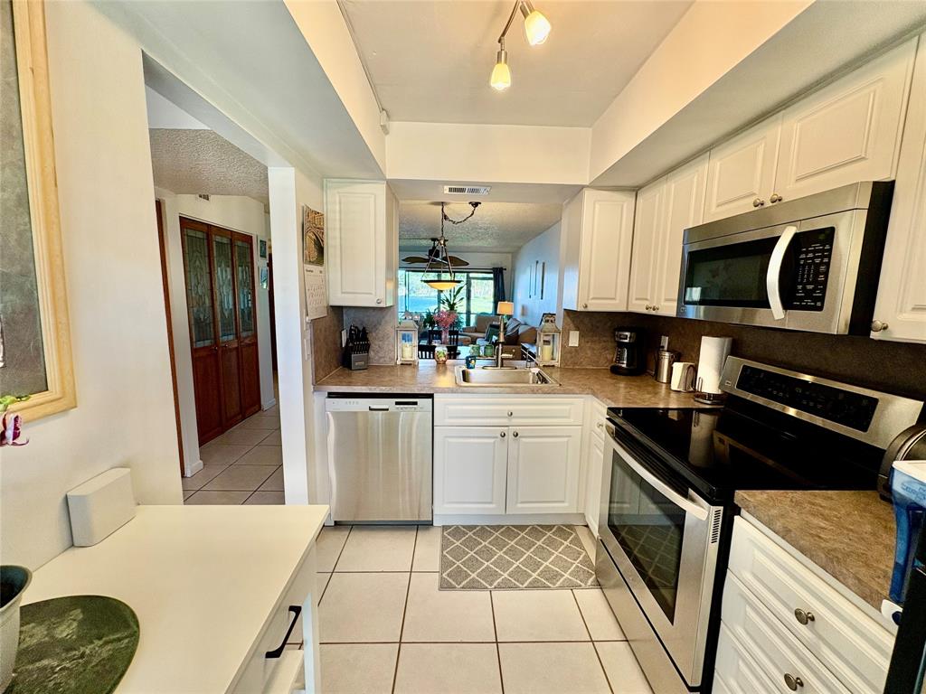 2249 Southwest 15th Street, Unit 185 Deerfield Beach, FL 33442 - Photo 14 of 31 a kitchen with stainless steel appliances granite countertop a stove a sink and a microwave