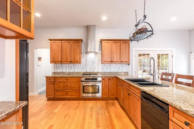 a kitchen with stainless steel appliances granite countertop a sink a stove and a wooden floors