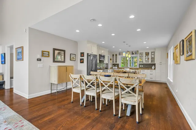 a kitchen with stainless steel appliances granite countertop a stove top oven a sink a stove a dining table and chairs with wooden floor